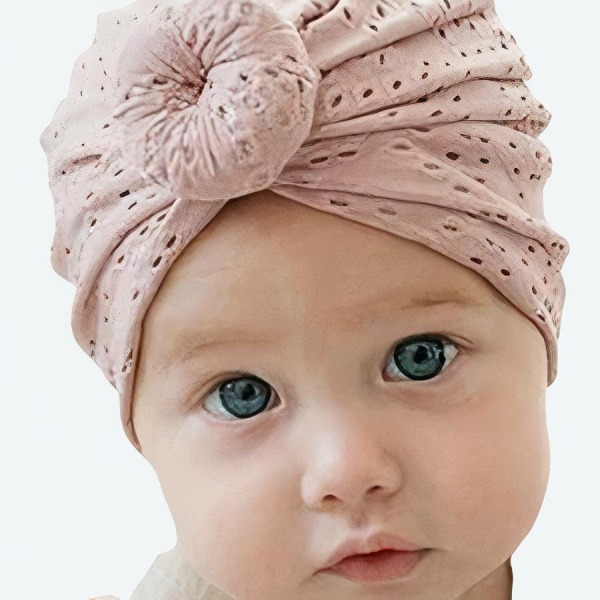 Petite fille qui porte un turban sur la tête avec un petit noeud sur le front , beige à trou