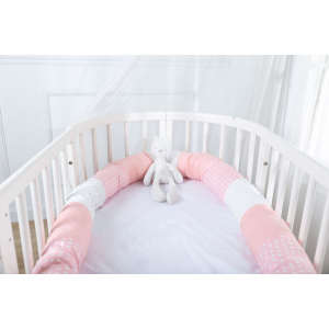 lit de bébé à barraux, blanc, avec un tour de lit rond, rose avec des motifs d'étoiles