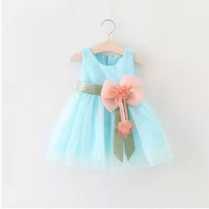 robe bleu clair pour bébé suspendue à un cintre sur un mur, avec une grosse fleur orangée à la taille