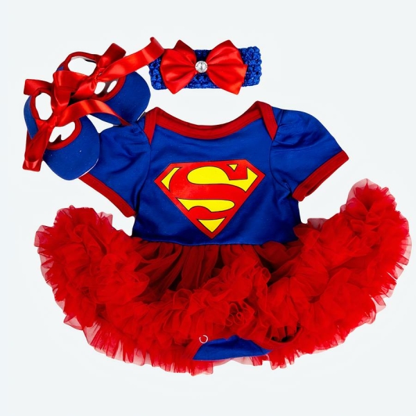 déguisement de super man pour bébé fille avec un body manches courtes et des volants rouges ,posé à plat sur fond blanc, au dessus sont posés des chaussons assortis et un bandeau avec un noeud