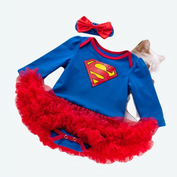 déguisement de super man pour bébé fille avec un body manches longues et des volants rouges ,posé à plat sur fond blanc