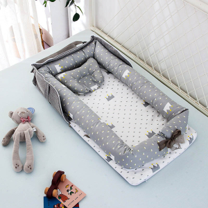 Réducteur de lit pour bébé gris avec motifs posé sur un lit avec des jouets et un doudou