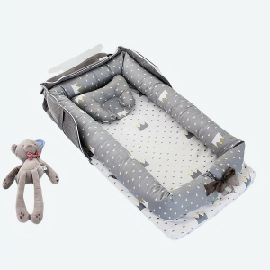 Réducteur de lit pour bébé gris avec motifs posé sur un lit avec des jouets et un doudou