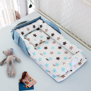 Réducteur de lit pour bébé bleu avec motifs étoiles, posé sur un lit avec des jouets et un doudou