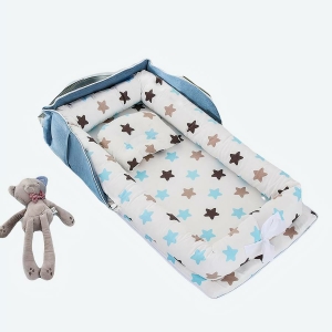 Réducteur de lit pour bébé bleu avec motifs étoiles, posé sur un lit avec des jouets et un doudou