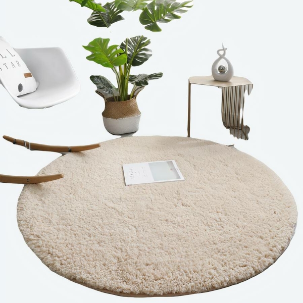 Un tapis beige rond posé au sol, sur le côté gauche une chaise à bascule et une plante dans un pot.