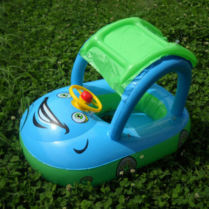 Bouée pour bébé avec pare-soleil de couleur turquoise et vert posée dans l'herbe