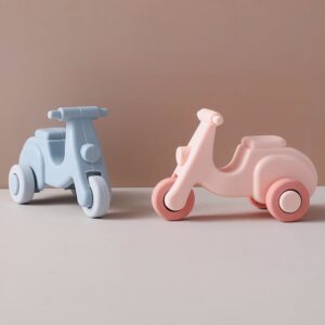 Un lot de 2 jouets sensoriels de dentition en forme de scooters bleu et rose, sur un fond couleur beige et taupe bicolore.